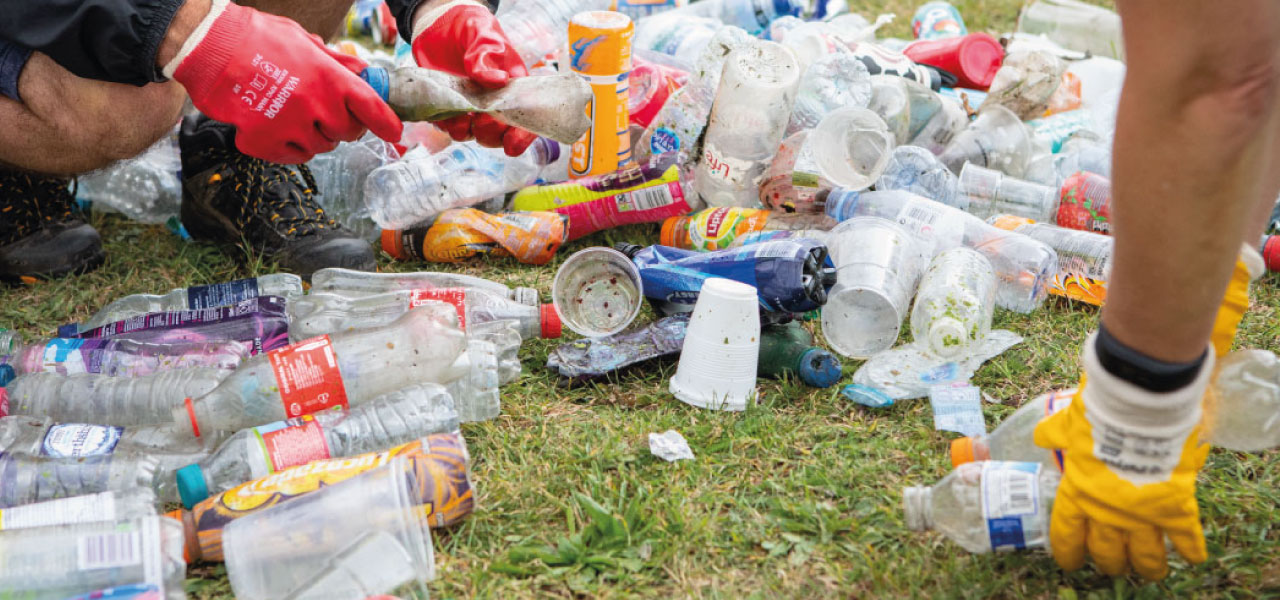 Hands with gloves counting littered plastic bottles